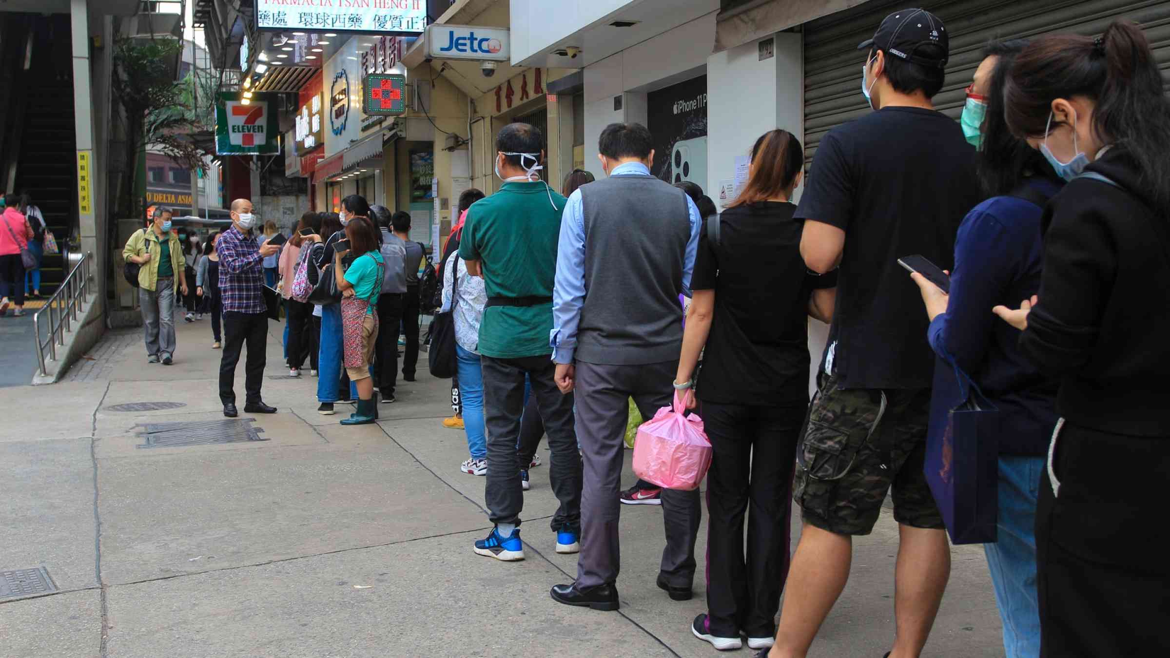 People in Macau, queue up to acquire face masks in a pharmacy